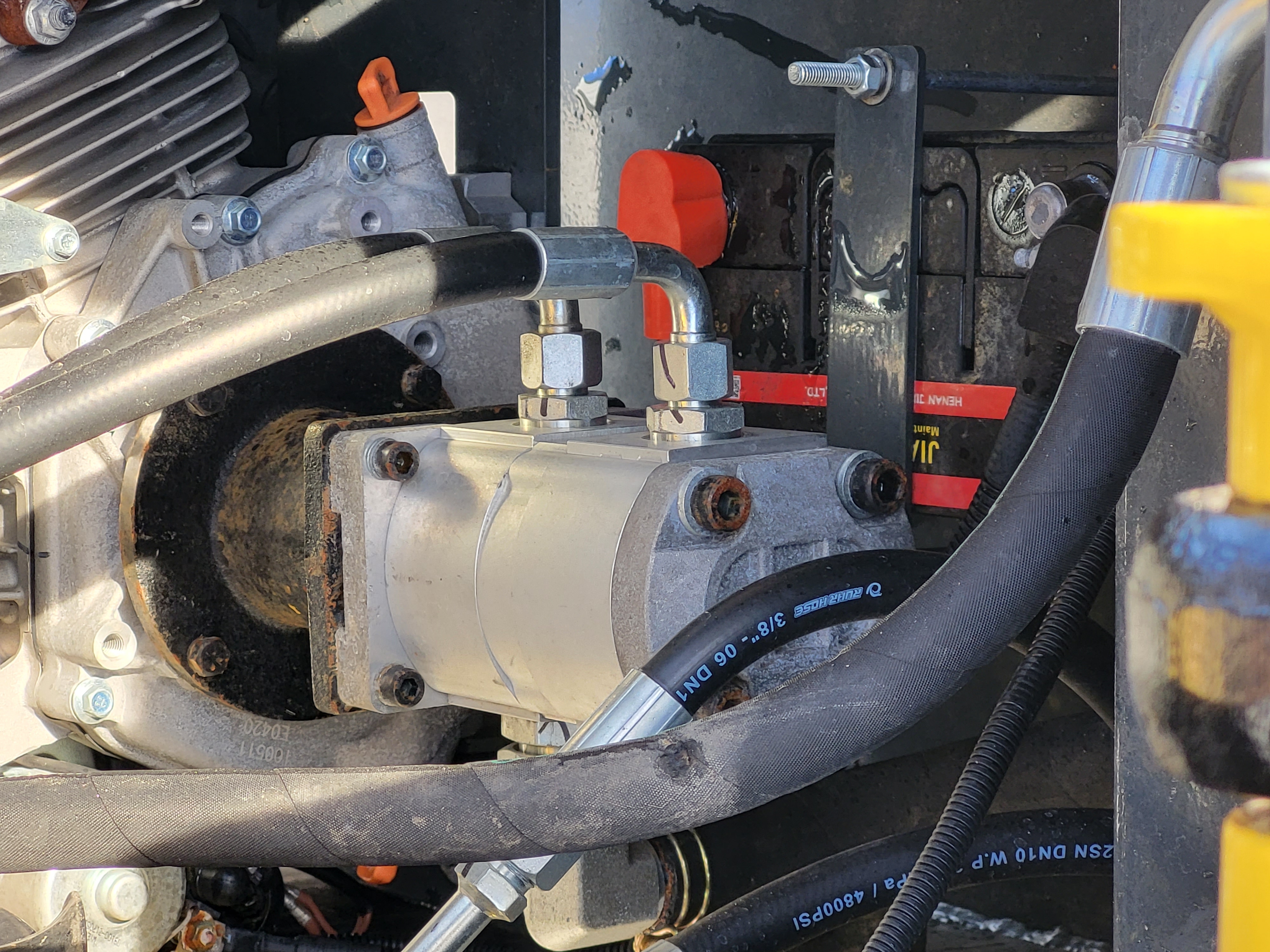 EG360 hydraulic gear pump bolted to the engine, with high-pressure hoses and the battery behind