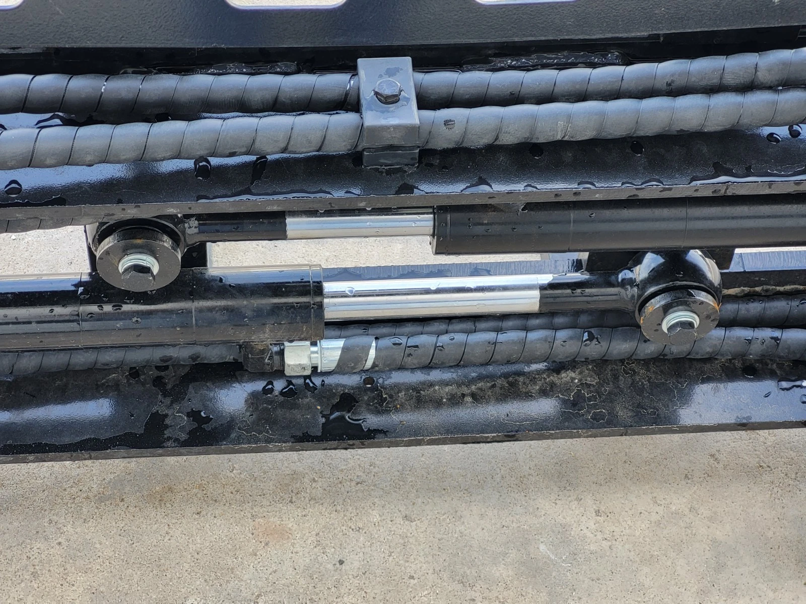 Twin hydraulic side-shift cylinders and sleeved hose runs behind the pallet fork backrest