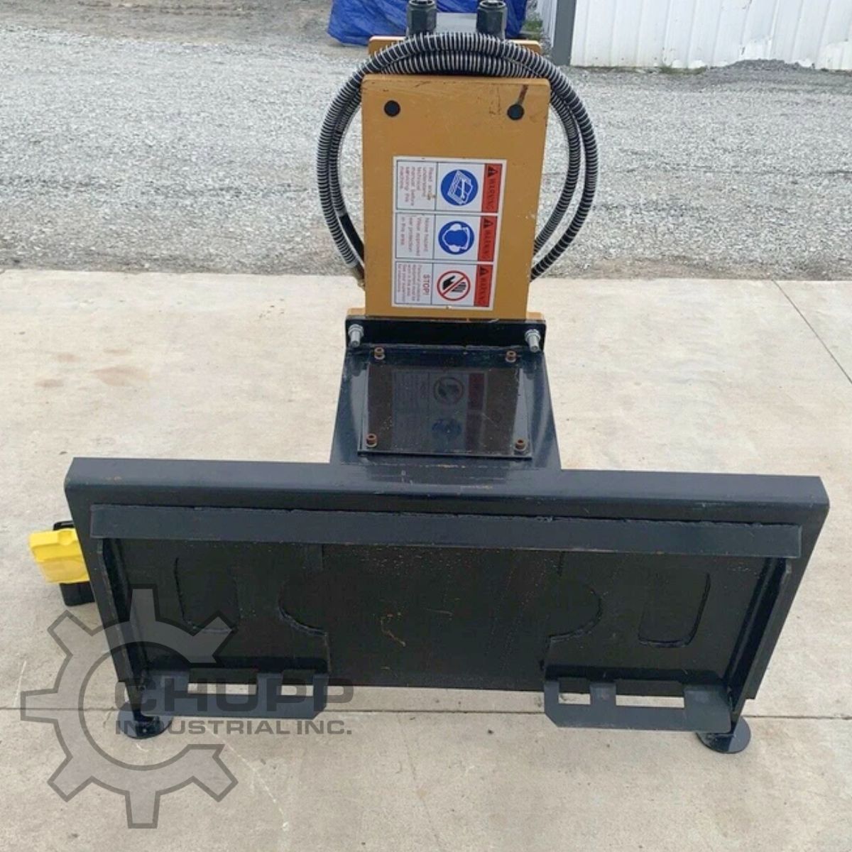 AGROTK 750 post driver from the mount side: universal skid steer quick-attach plate and the hammer's safety decals