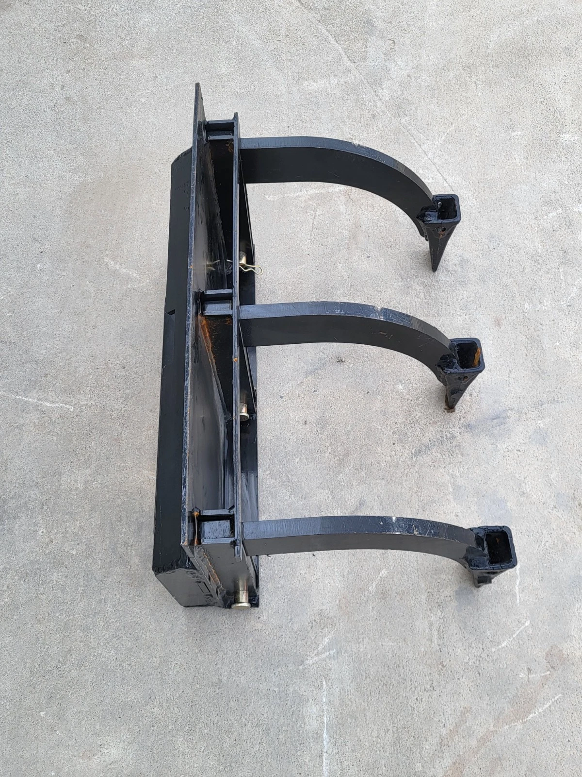 Three-tooth ripper on its side: mount plate, cross bar and three curved shanks with square boot tips