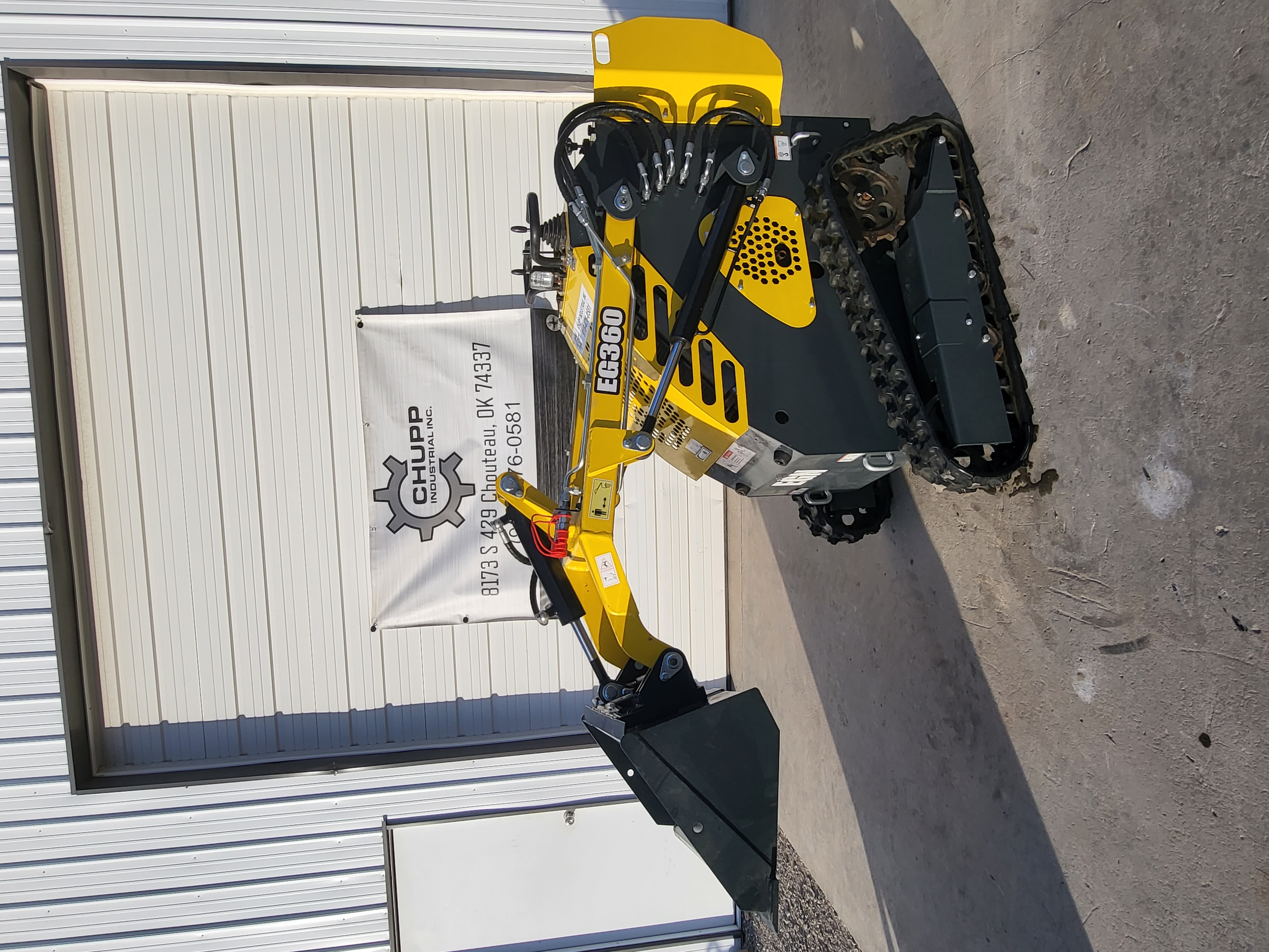 EG360 mini skid steer with the loader arms partly raised and the bucket tilted forward on the rubber tracks