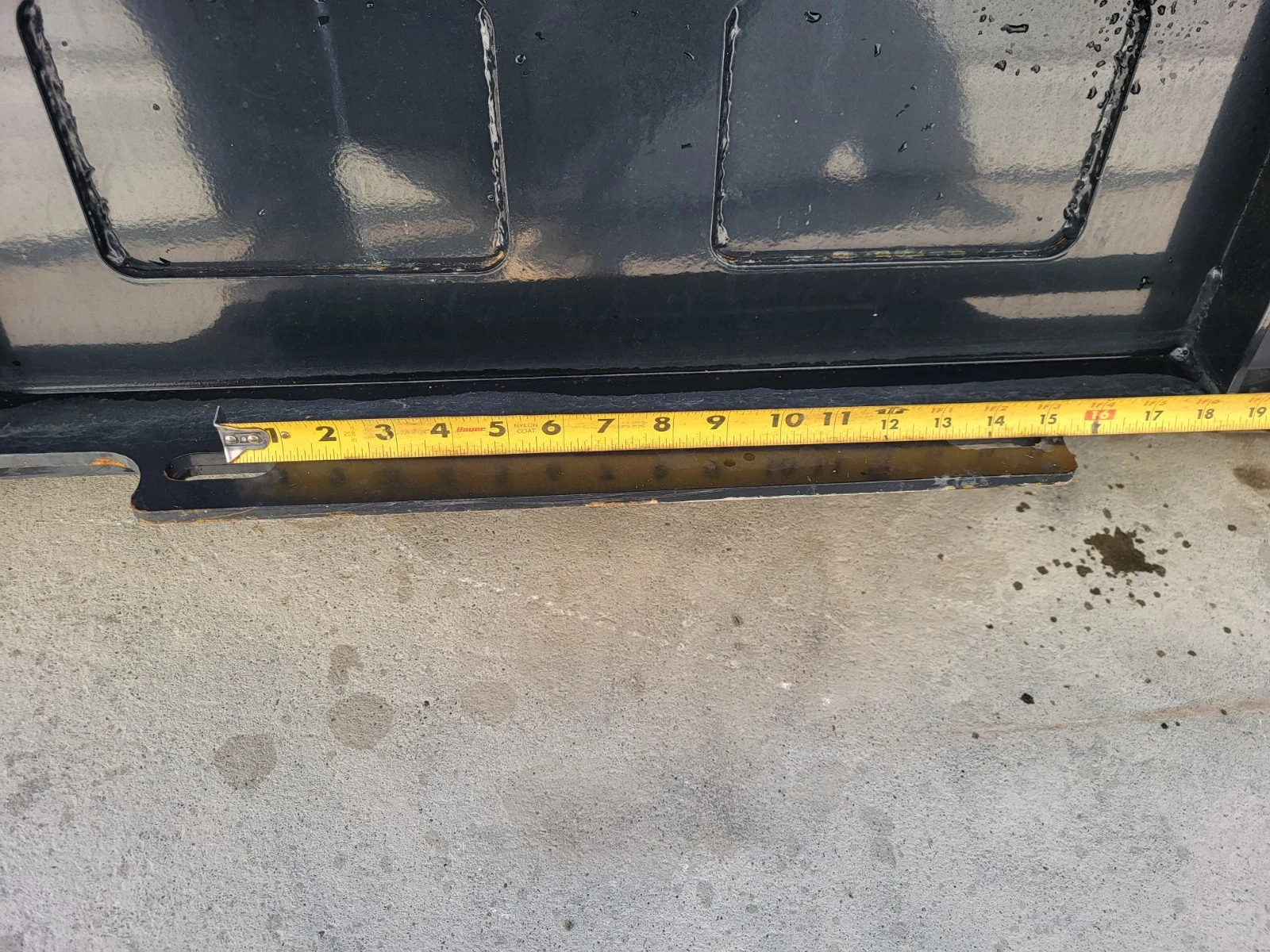 Tape measure along the bucket's bottom edge below the mount plate, reading about 19 inches