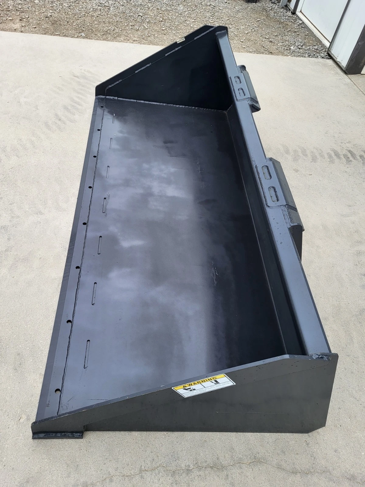 Skid steer bucket at an angle: interior floor with bolt slots, side walls and quick-attach brackets