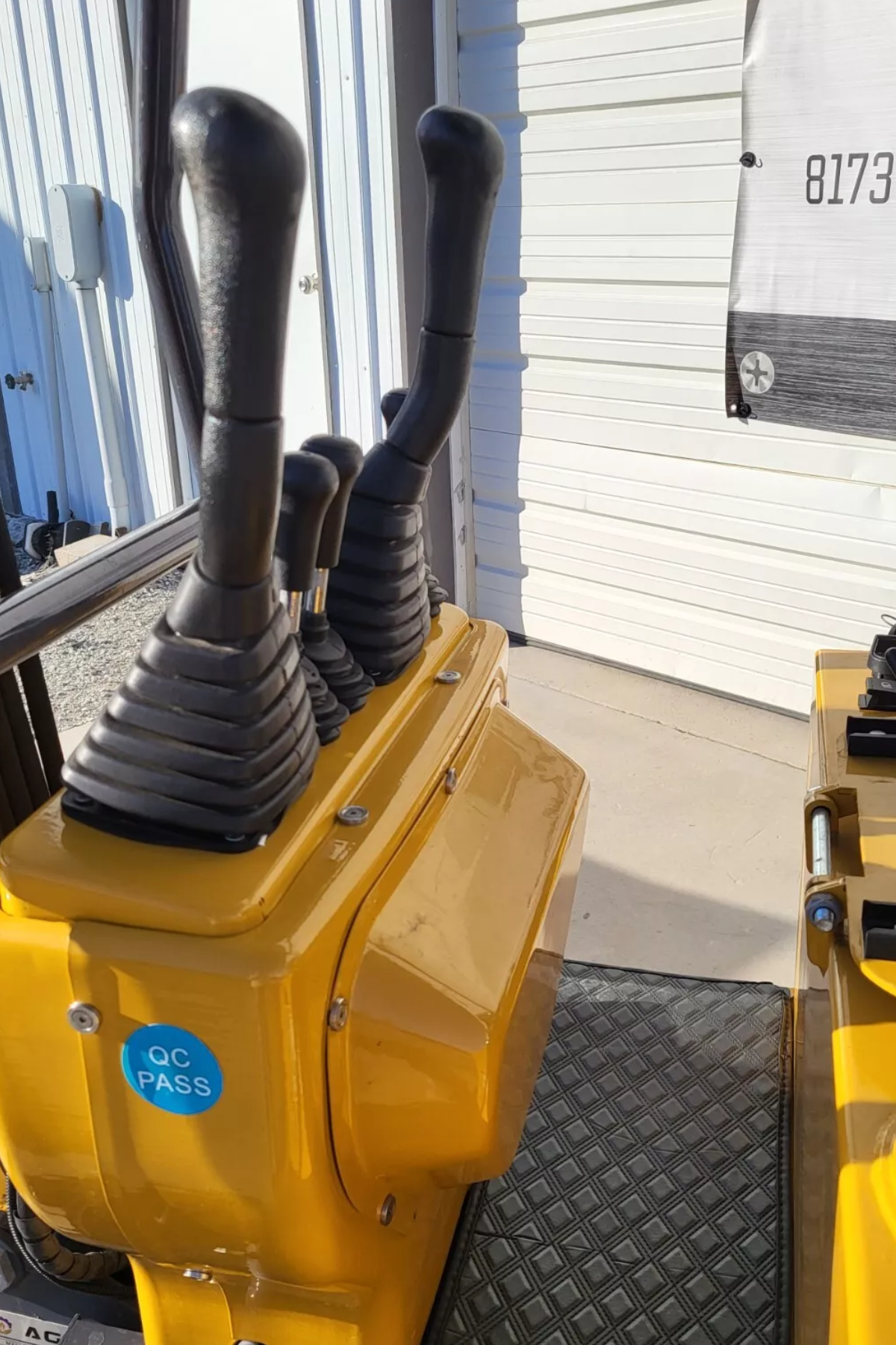 AGT MX12R mini excavator control stand with booted steel hand levers on the yellow console and the rubber floor mat