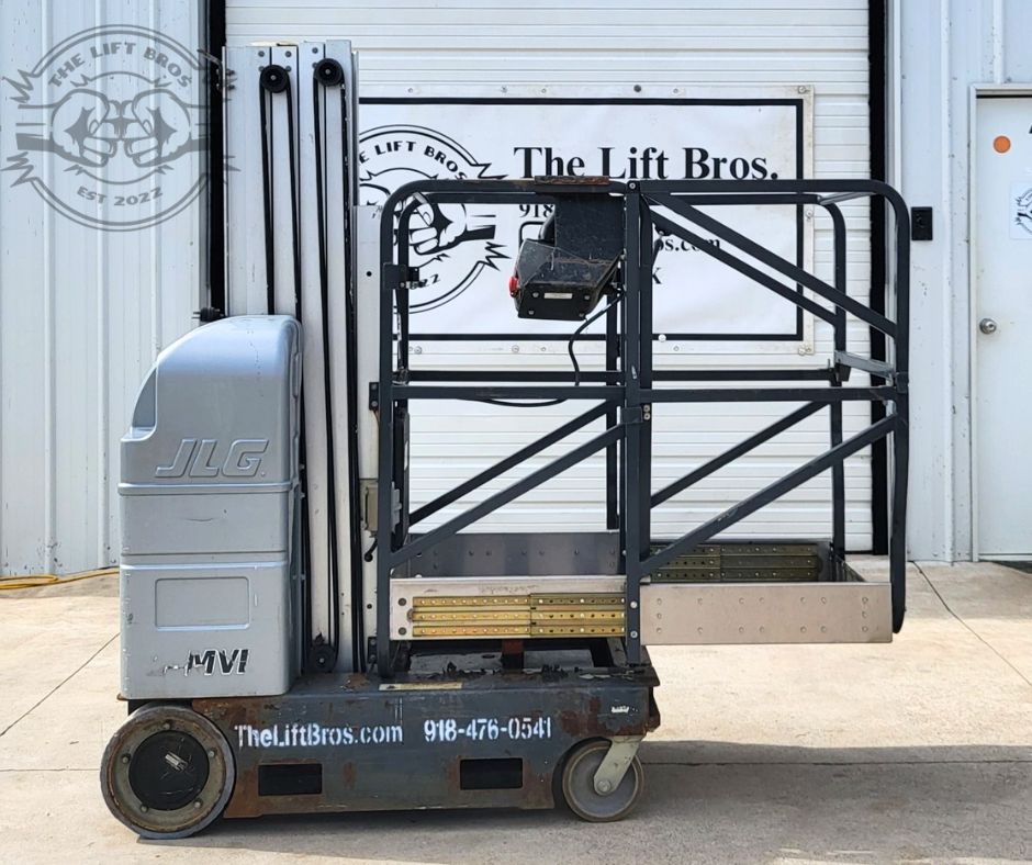 JLG vertical mast lift, silver power unit, black guardrails around the platform, mast lowered, four wheels