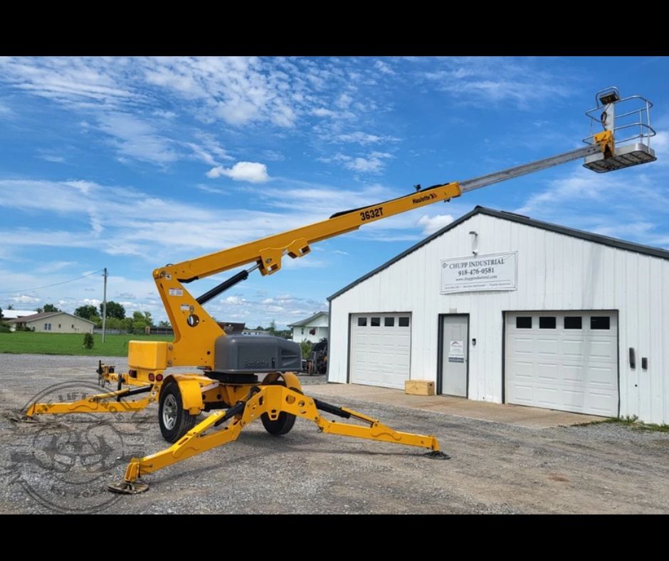 Yellow Haulotte 3632T towable boom lift with the boom raised and telescoped out over its outriggers