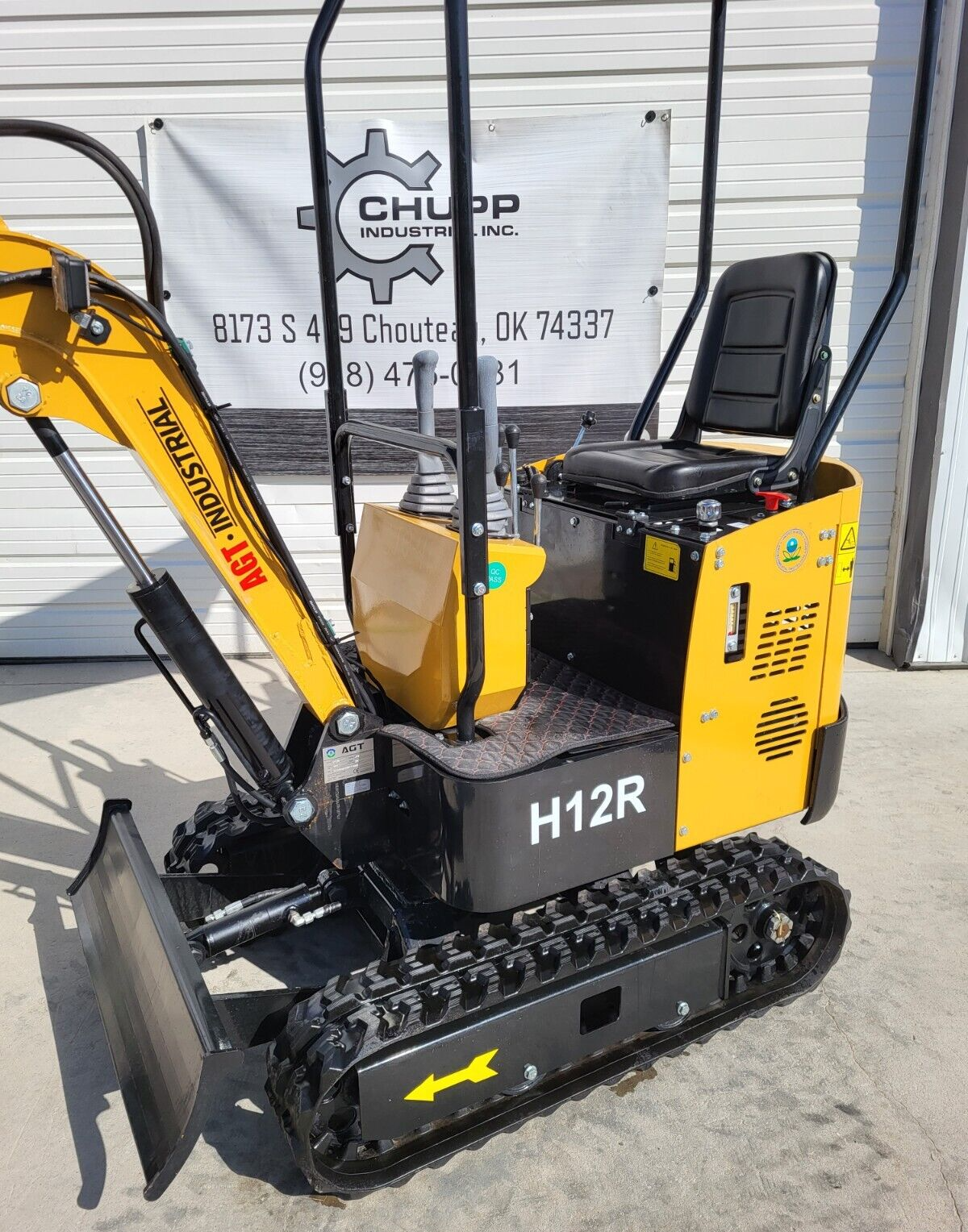 Yellow AGT H12R mini excavator with backfill blade, rubber tracks, open operator seat and roll bar canopy