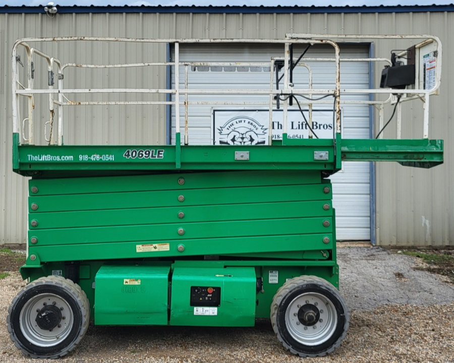 Green JLG 4069LE rough terrain scissor lift, side profile, platform lowered on folded green scissor stack