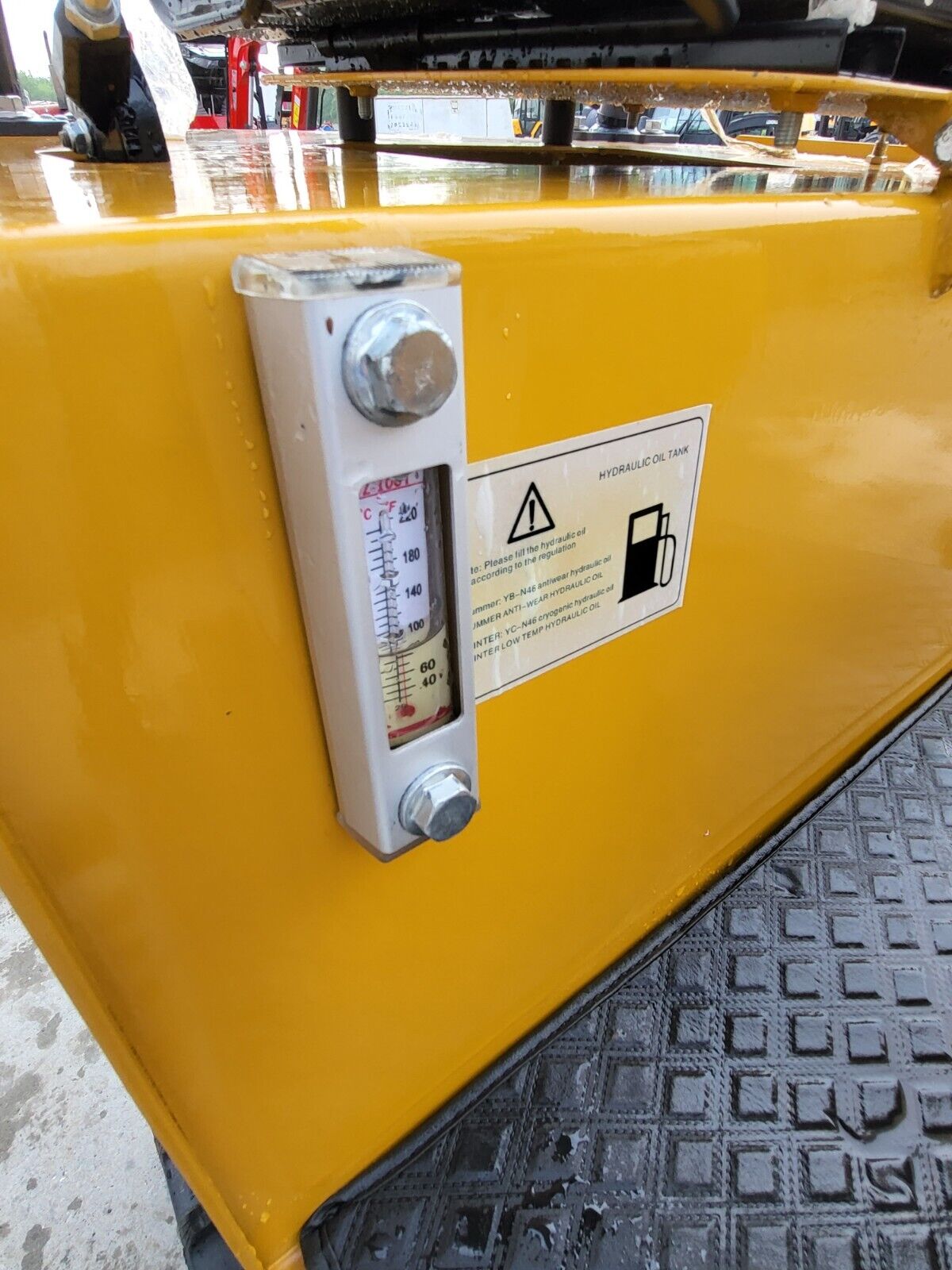 DM12-C hydraulic oil tank: sight glass level gauge with temperature scale and the fill-spec decal on the yellow body