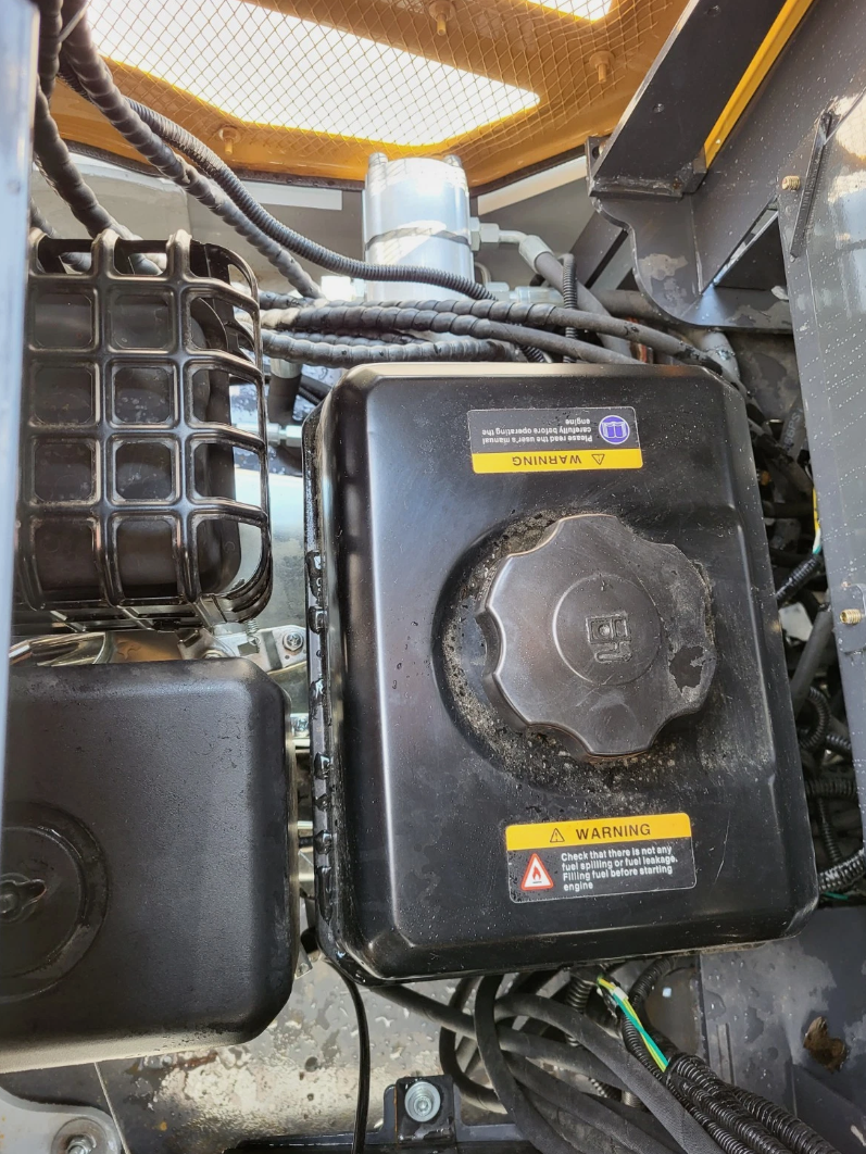 IRE18P fuel tank with cap and warning labels beside the air filter housing in the engine bay