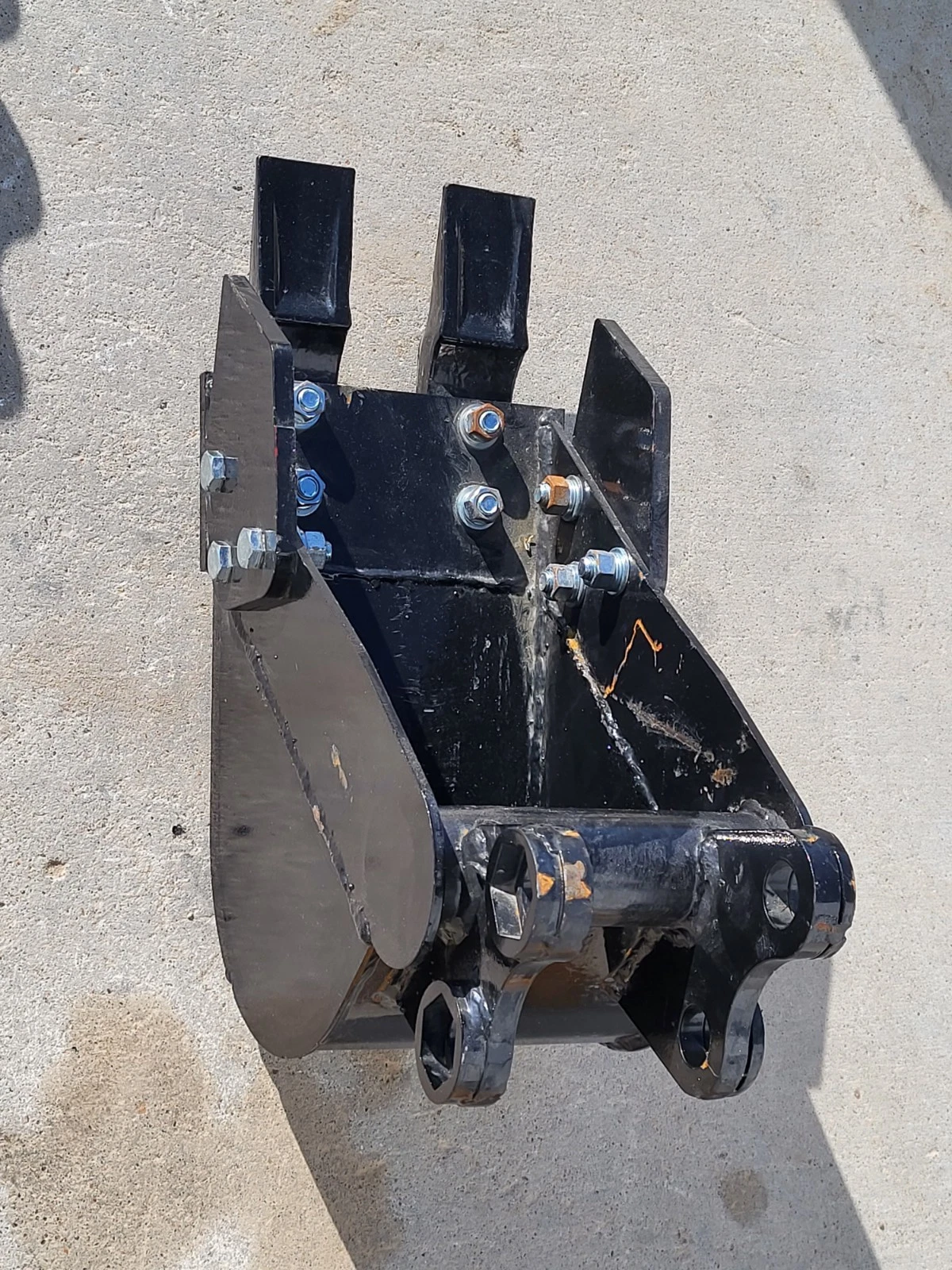 Black 8-inch trenching bucket, digging teeth and side cutter plates, bolt-on pin hitch at the back