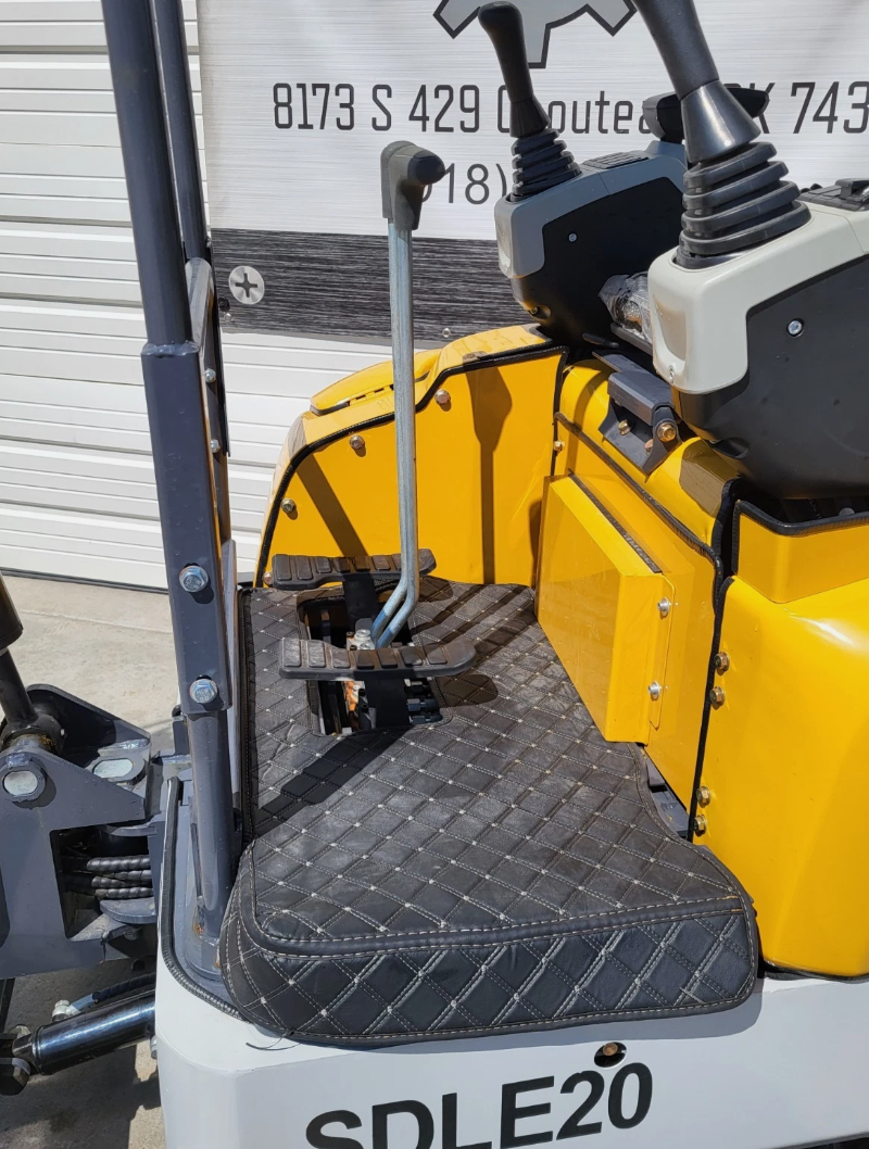 SDLE20 mini excavator operator floor: quilted mat, travel pedals and levers, blade lever and pilot joystick console