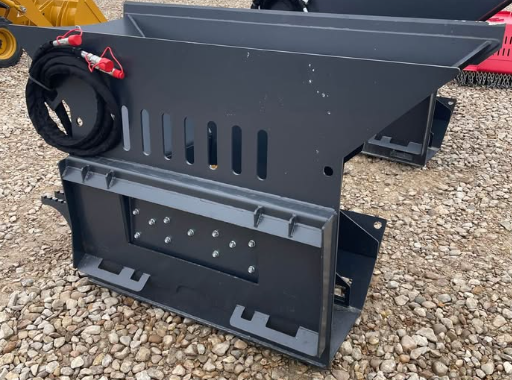 WIG asphalt block crusher: gray steel hopper with slotted vents, quick-attach mount and coiled hydraulic hoses