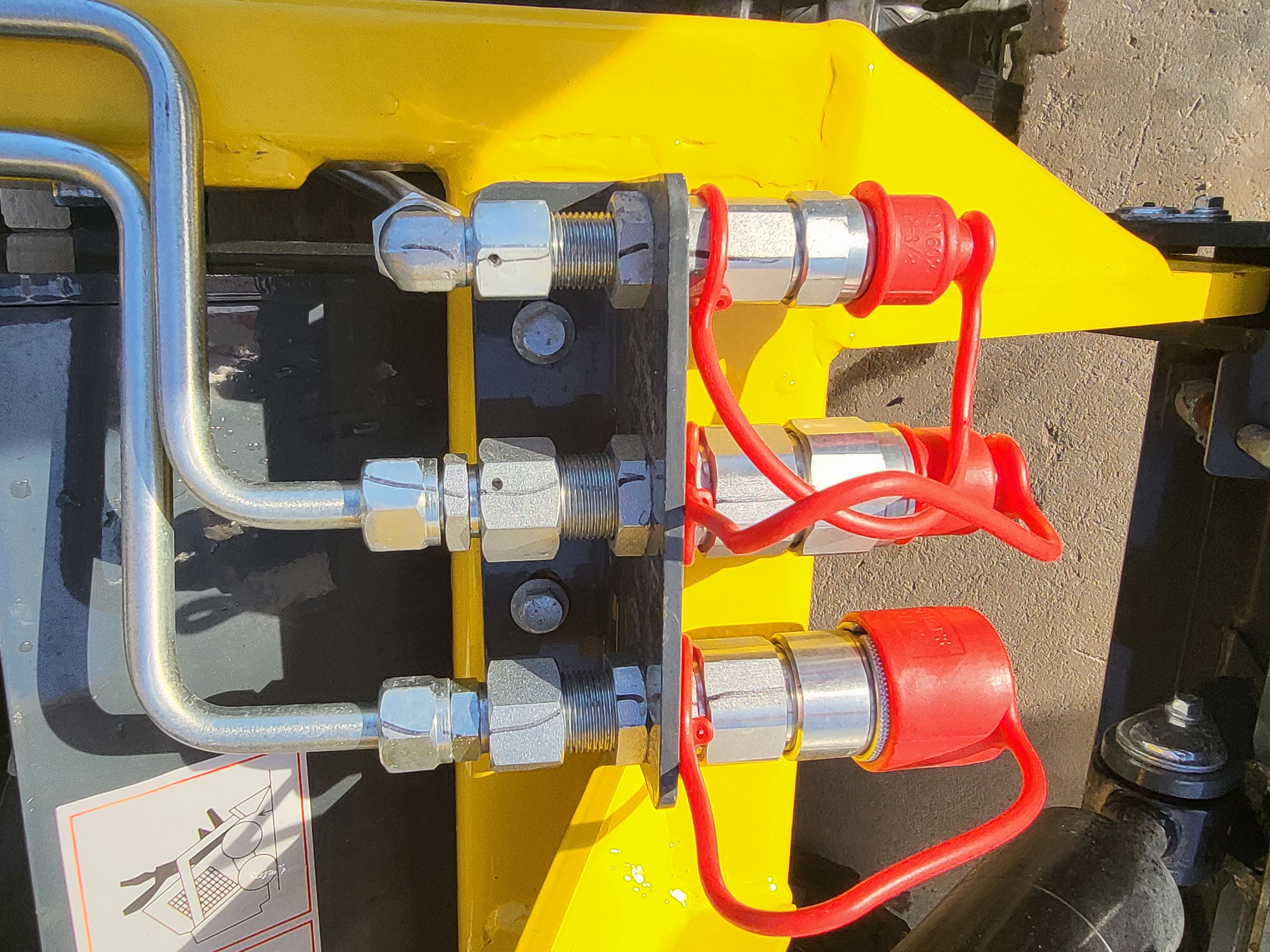 EG360 auxiliary hydraulic quick couplers with red dust caps on the yellow loader arm
