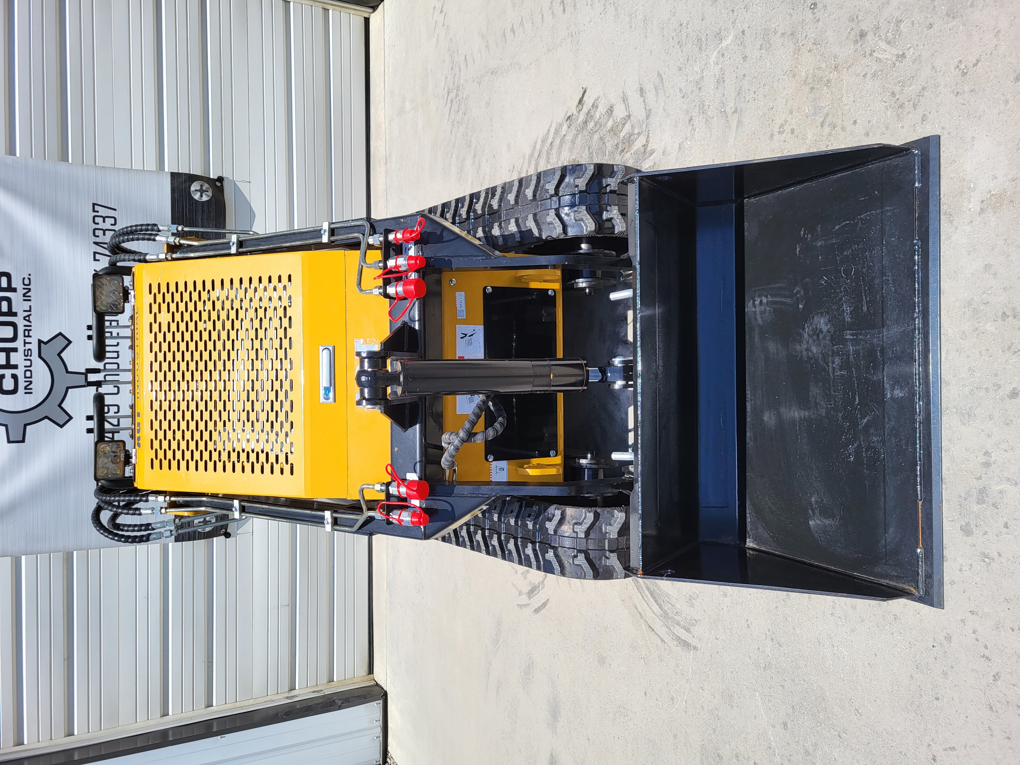AGT CRT23 head-on: wide black bucket, loader arms, red-capped auxiliary couplers and perforated engine hood