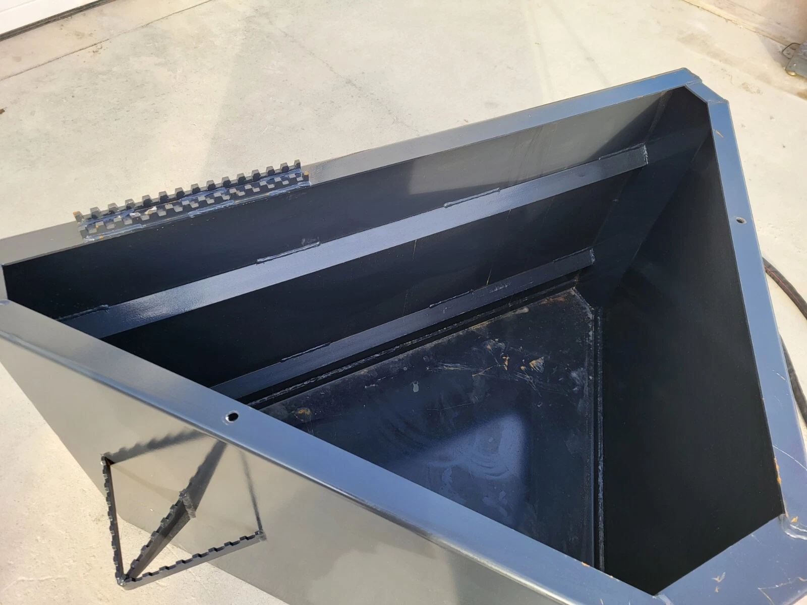 Inside the concrete bucket: steel cross braces over the hopper and serrated step plates on the rim