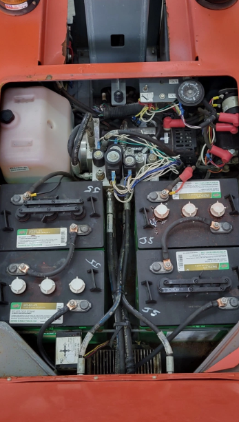 Skyjack SJ16 open battery bay: six lead-acid batteries, wiring harness and hydraulic hoses