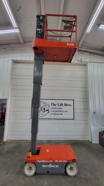 Orange Skyjack SJ16 with platform raised and mast extended to full height indoors