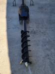 Wolverine post hole auger gearbox and black helical auger bit with cutting teeth at the tip