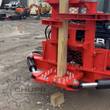 Red tree shear mounted on a JCB skid steer, blades closed around a wooden post at ground level