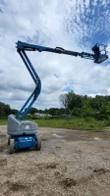 Genie articulating boom lift with the boom raised and reaching out over open ground
