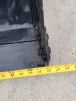 Tape measure at the 4-in-1 bucket's bottom corner reading 38 inches across the bucket width