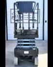 Genie GS-1930 scissor lift from behind, black platform lowered over the silver scissor stack, guardrails up