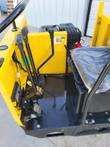 Mini dumper operator station: control levers, foot pedal, plastic-wrapped seat and gas engine behind the dash
