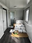 Portable office interior with sink cabinet, frosted-glass bathroom door and packaged materials on the floor