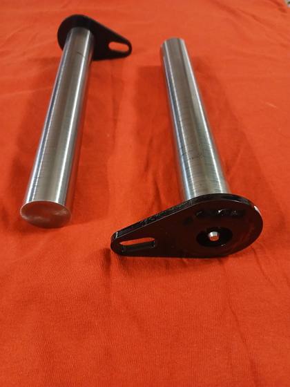 Two hardened steel lift arm pins with black flag plates, one with a countersunk grease fitting