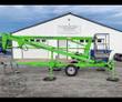 Green Nifty TM34 towable boom lift folded on its trailer with outriggers down and tow coupler