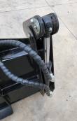 Clam cylinder rod and pivot pin at the corner of the 4-in-1 bucket, hoses running across the shell