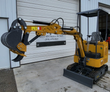 Yellow AGT H15 mini excavator, boom out with digging bucket and thumb, backfill blade down, canopy over the seat