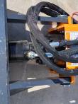 Auger drive's black motor housing bolted to the orange gearbox, sleeved hydraulic hoses looped over the mount frame