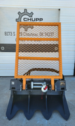 Arteer logging winch, front view: orange mesh guard over the cable drum and hook, toothed anchor blade below