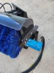 Blue hydraulic drive motor bolted to the angle broom's end plate, driving the blue bristle roller