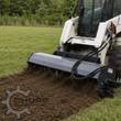 Wolverine tiller mounted on a skid steer, tines breaking sod into loose soil