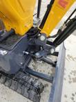 DM12-C boom swing bracket: pivot pin, swing cylinder and routed hydraulic hoses above the rubber track and dozer blade
