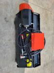 Flail mower from above with coiled hydraulic hoses and capped quick couplers on the black deck