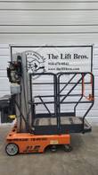 Orange JLG 12SP push-around vertical mast lift, lowered, side view with hydraulic power unit and battery box
