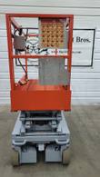 Skyjack scissor lift lowered, end view of the platform with control box, warning decals and chassis tow loops