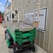 JLG 3246ES wide silver platform deck and rails above green scissor stack, end view