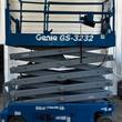 Genie GS-3232 scissor lift partly raised, gray scissor stack under blue platform