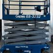 Genie GS-3232 scissor lift partly raised, gray scissor stack under blue platform