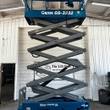 Genie GS-3232 scissor lift raised to full height, gray scissor stack under blue platform