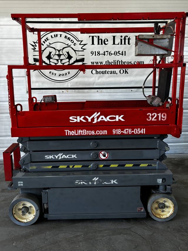 Red and gray Skyjack 3219 electric scissor lift, stowed, side view with platform rails and Skyjack decals