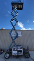 Genie GS3369 RT scissor lift raised to full height, looking up the scissor stack to the platform underside