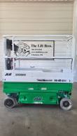 Green and white JLG 1930ES electric scissor lift, stowed, side view with platform rails and control box