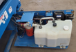 Genie scissor lift power module: white hydraulic reservoir, red spin-on filter, pump lines and relays