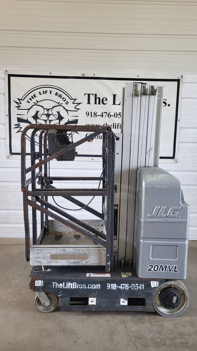 Gray JLG 20MVL vertical mast lift, stowed, side view with rusty guardrail platform and battery cover